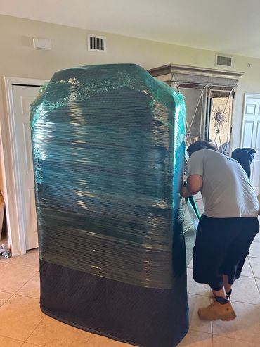 Person wrapping furniture for moving or protection.