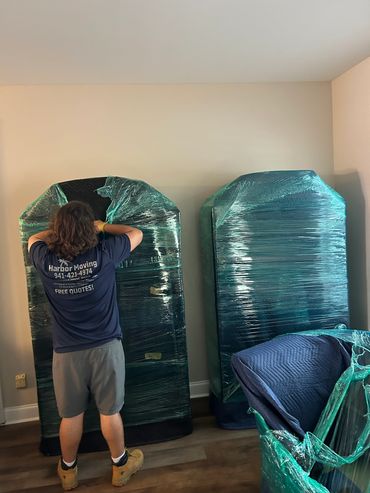 Mover wrapping furniture in plastic wrap.