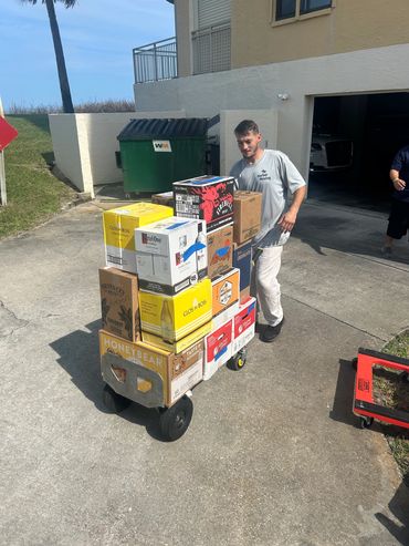 Man pushing a loaded cart full of boxes outdoors.