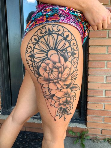 feminine black and gray tattoo of fine line peonies with black ironwork in the background on a hip