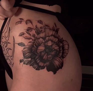 painterly feminine black and gray flower tattoo on a hip