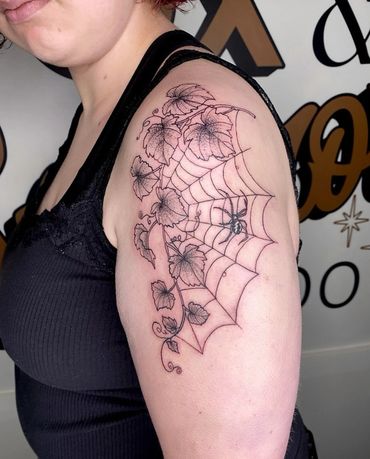 fineline black and gray spiderweb with vines and leaves and a black widow tattoo