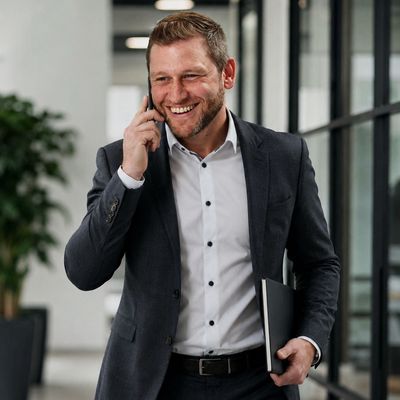 Smiling businessman talking on phone while walking in office.