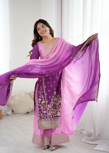 Woman in a vibrant purple and pink traditional outfit gracefully holding a matching dupatta.