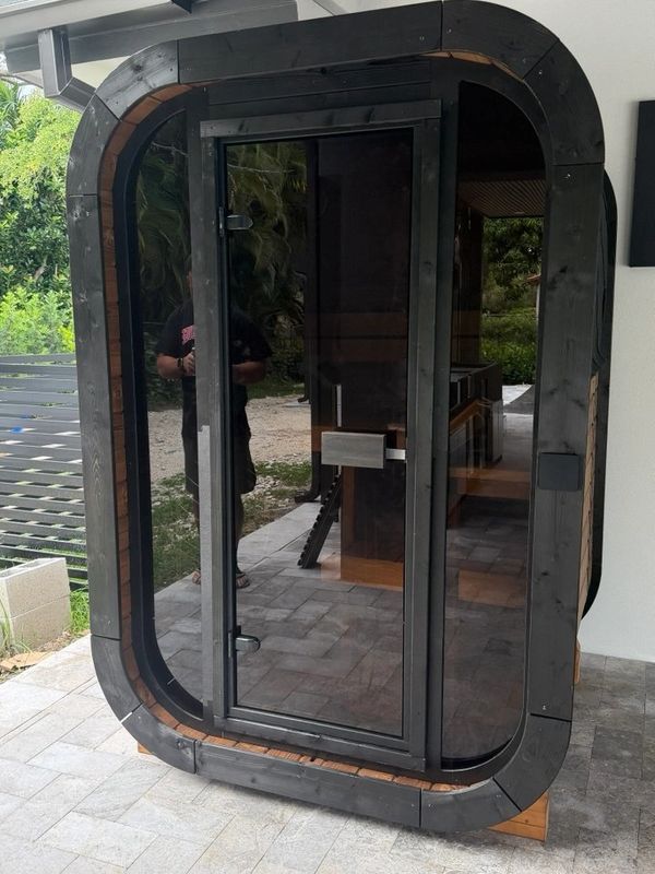 Modern black-framed glass door structure with a rounded rectangular design.