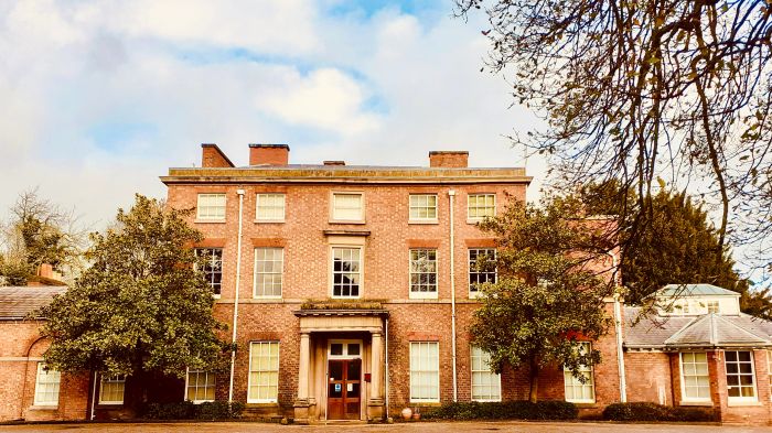 A large brick building with multiple windows and trees in front.