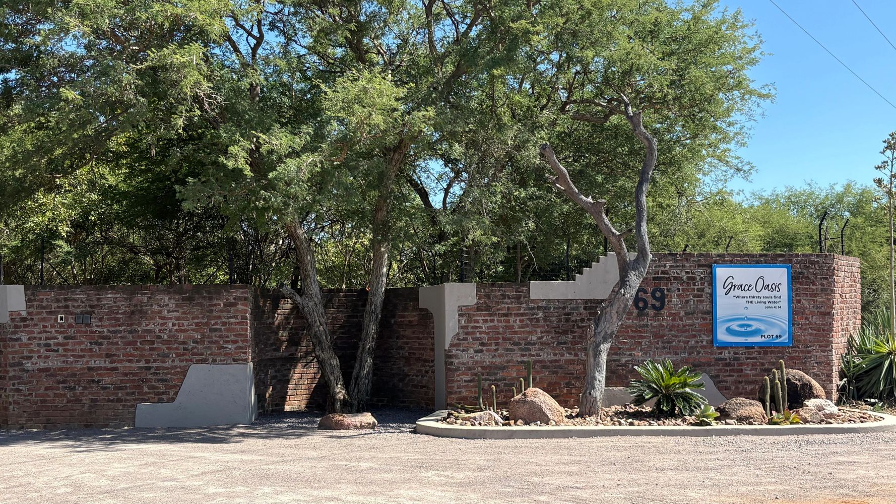 Brick wall entrance with trees and a sign for Grace Oasis.