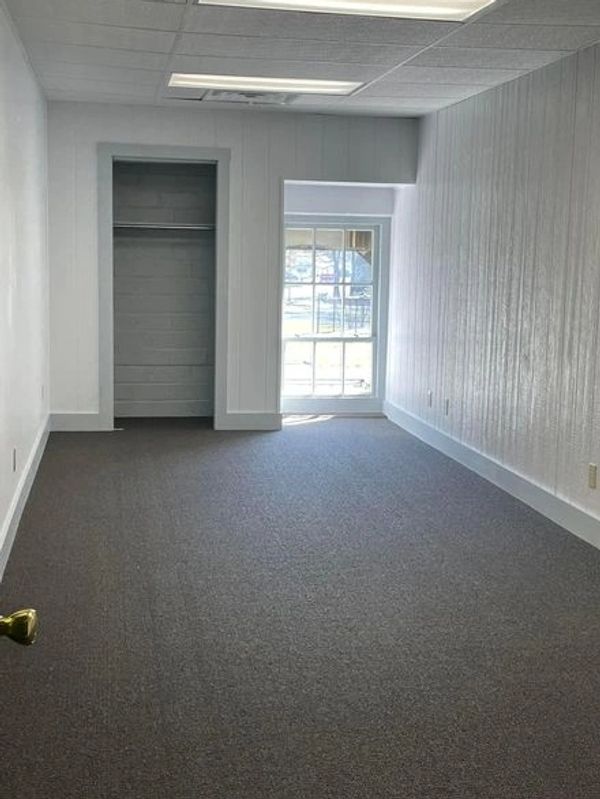Empty room with gray carpet, white walls, and a small closet.