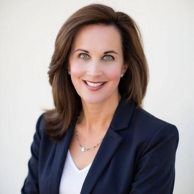 Professional woman smiling in business attire against a plain white background.