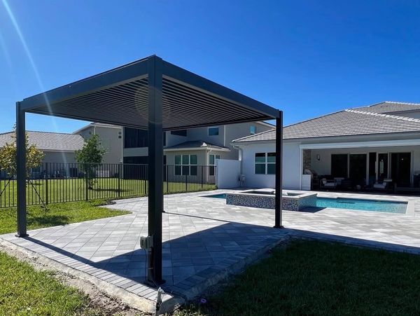 Modern backyard with a sleek pergola, pool, and patio area under a clear blue sky.