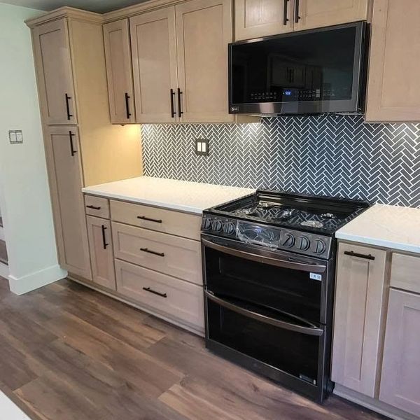 Modern kitchen with light wood cabinets and black appliances.