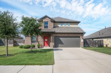 Modern two-story brick house with a red front door and a spacious driveway.