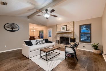 Cozy living room with white sofa, stone fireplace, and wooden floors.
