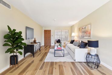 Modern living room with a white sofa, wooden floor, and stylish decor.