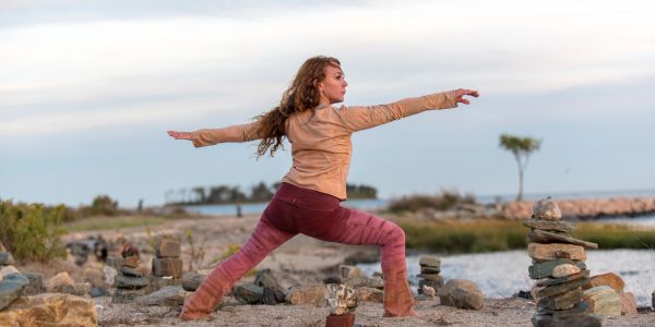 Woman practicing yoga outdoors near a lake.