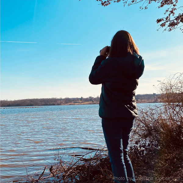 Alexandra Wisser looking through binoculars by a pond