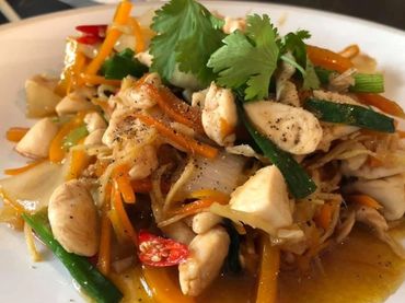 Stir-fried chicken with vegetables and herbs on a white plate.