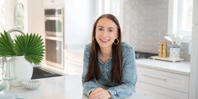 Smiling woman leaning on a kitchen counter.