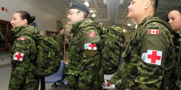 Canadian military medical personnel in uniform with red cross patches and backpacks.