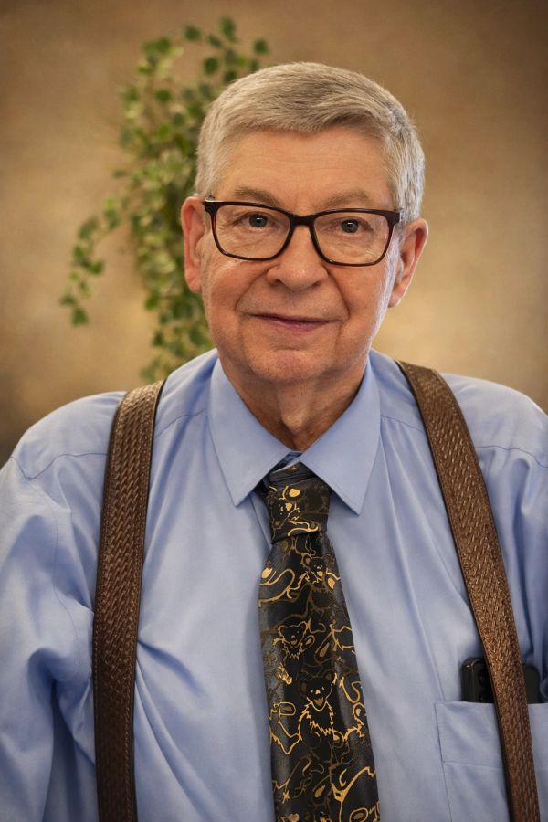 Smiling elderly man with glasses and suspenders.