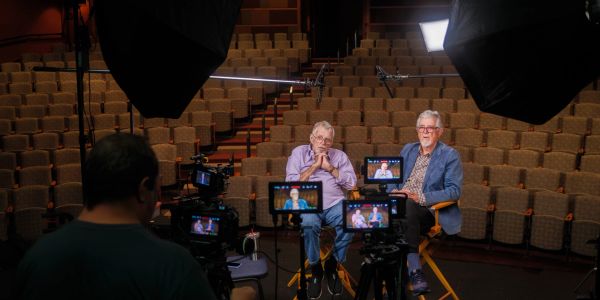 Two men being filmed in an empty theater.