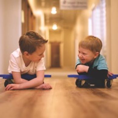 Two kids are playing using methods of integration of primitive reflexes and physical therapy