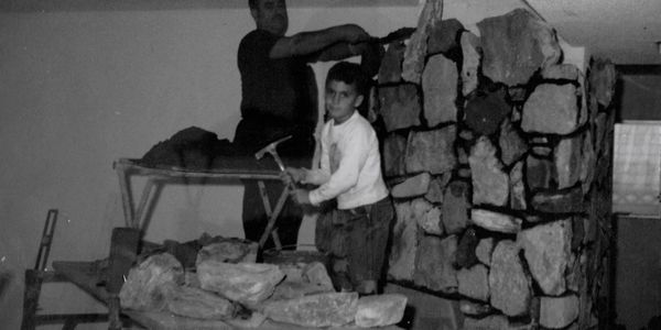 John at age 7 helping his father build a fireplace.