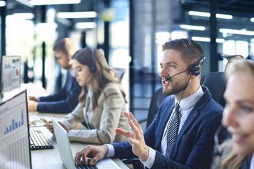 Customer service representatives working with headsets in a modern office.