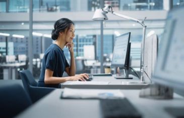 A woman working intently on a computer in a modern office.