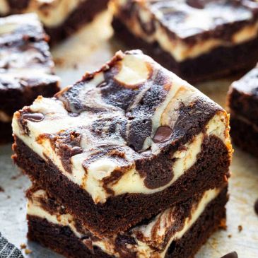 Two stacked chocolate and cream cheese swirl brownies with chocolate chips.
