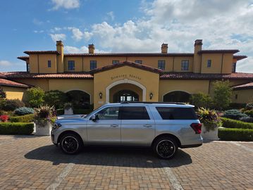 Silver SUV parked in front of Domaine Serene winery on a sunny day.