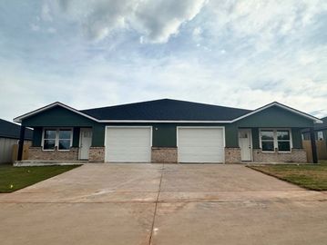 A modern duplex with two garages under a cloudy sky.