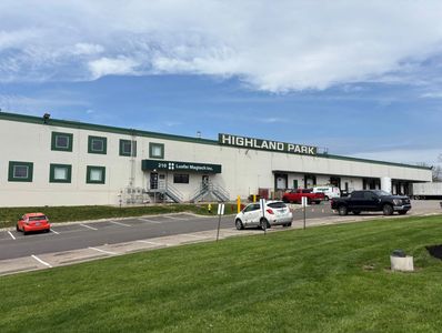 Exterior of Highland Park industrial building with parked vehicles.