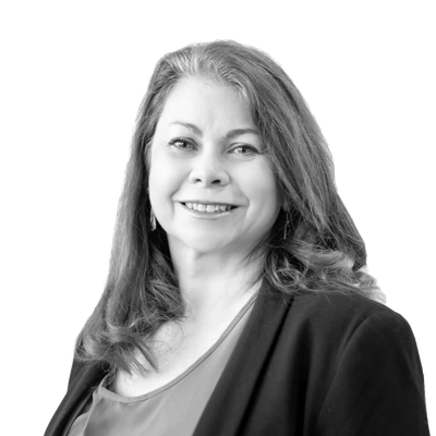 Smiling woman with long hair in professional attire against white background.