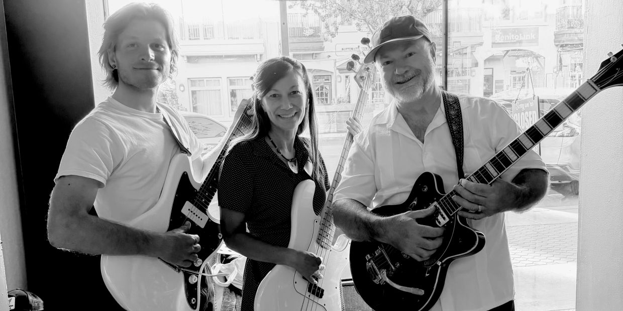 Three musicians posing with guitars in black and white.