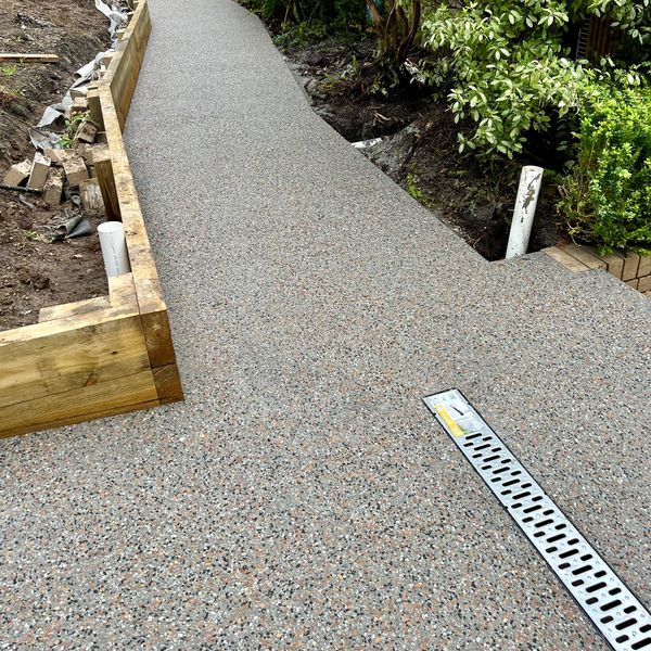 Newly paved concrete pathway with drainage grate.