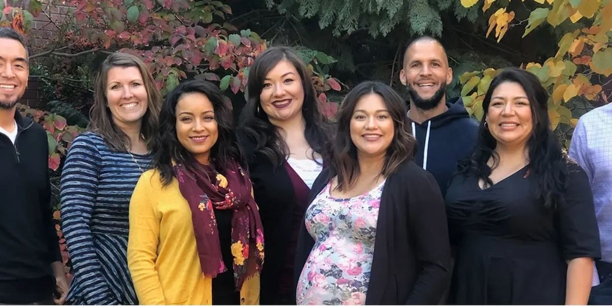 A group of diverse people smiling outdoors in autumn.