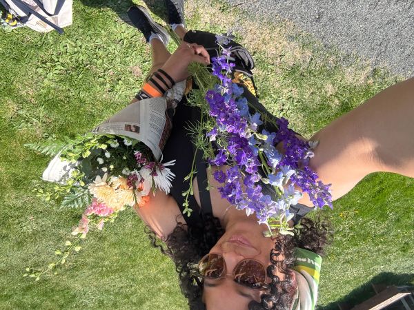Young woman holding two bouquets of colorful flowers outdoors.