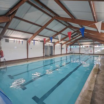 Indoor swimming pool with wooden beams and colorful flags.