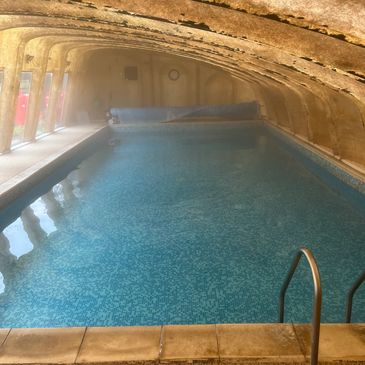 Indoor swimming pool with arched ceiling and blue tiles.