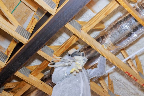 Technician spraying foam in attic rafters