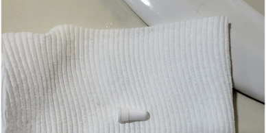 A white capsule pill on a ribbed cloth by a sink.