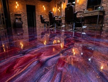Shiny, swirled epoxy floor with red and purple hues in a modern salon.