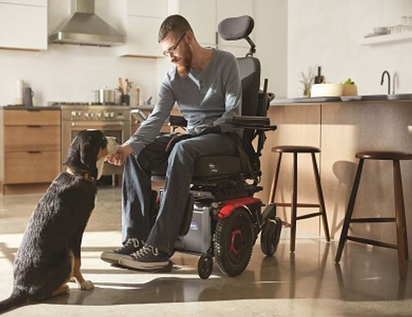 Man in wheelchair patting dog