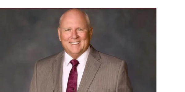 Smiling man in a suit and tie posing for a formal portrait.