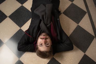 A top down aerial photograph of me on a checkered tile floor with my arms crossed behind my head.