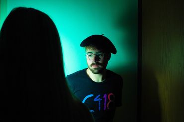 A photograph of myself being casted in a teal light while a dark silhouette is seen in front of me.