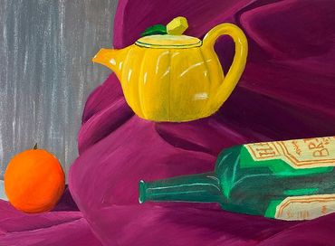 A yellow teapot, green glass bottle, and an orange placed on a piece of quinacridone violet fabric.