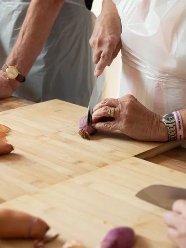 Group of people chopping shallots on wooden cutting boards in a cooking class.