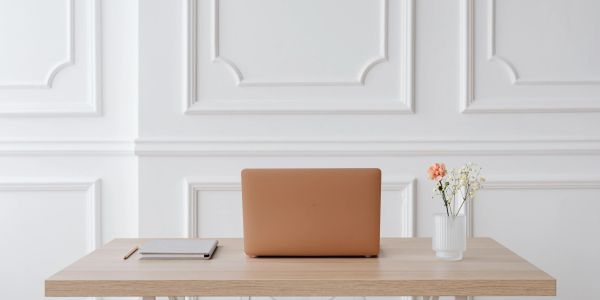 Neat minimalist desk setup with laptop and flowers.